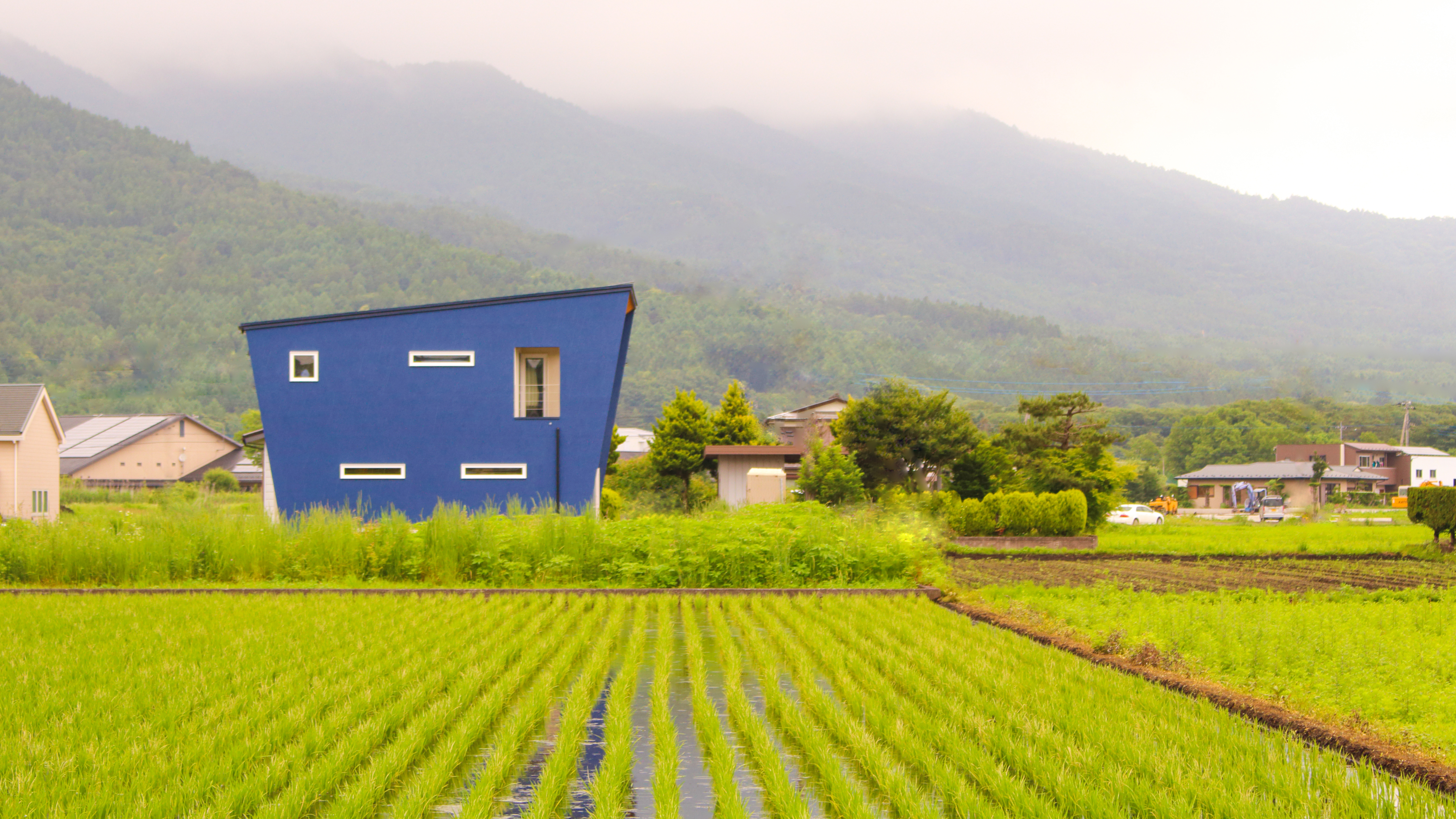 山梨県南都留郡忍野村の家。ネイビーの塗り壁で四角いお家ではなく、台形を逆にしたおしゃれな外観。